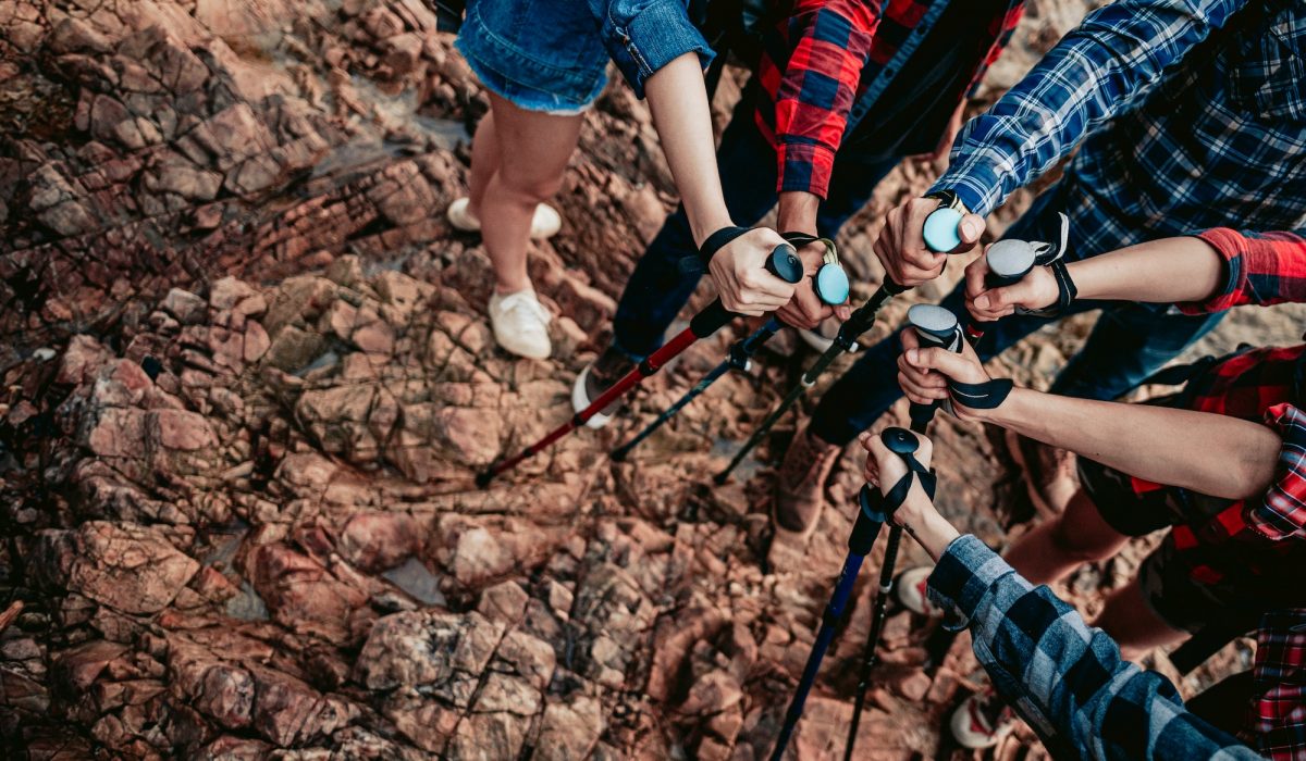 A group of hikers holding trekking sticks join together as a team.Teamwork , travel trekking